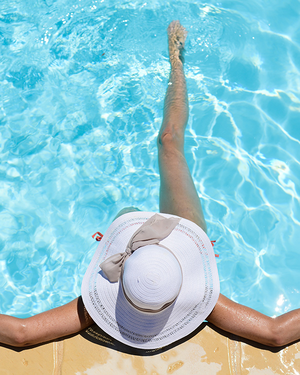 Top-down view of a woman in a white hat sitting in a pool